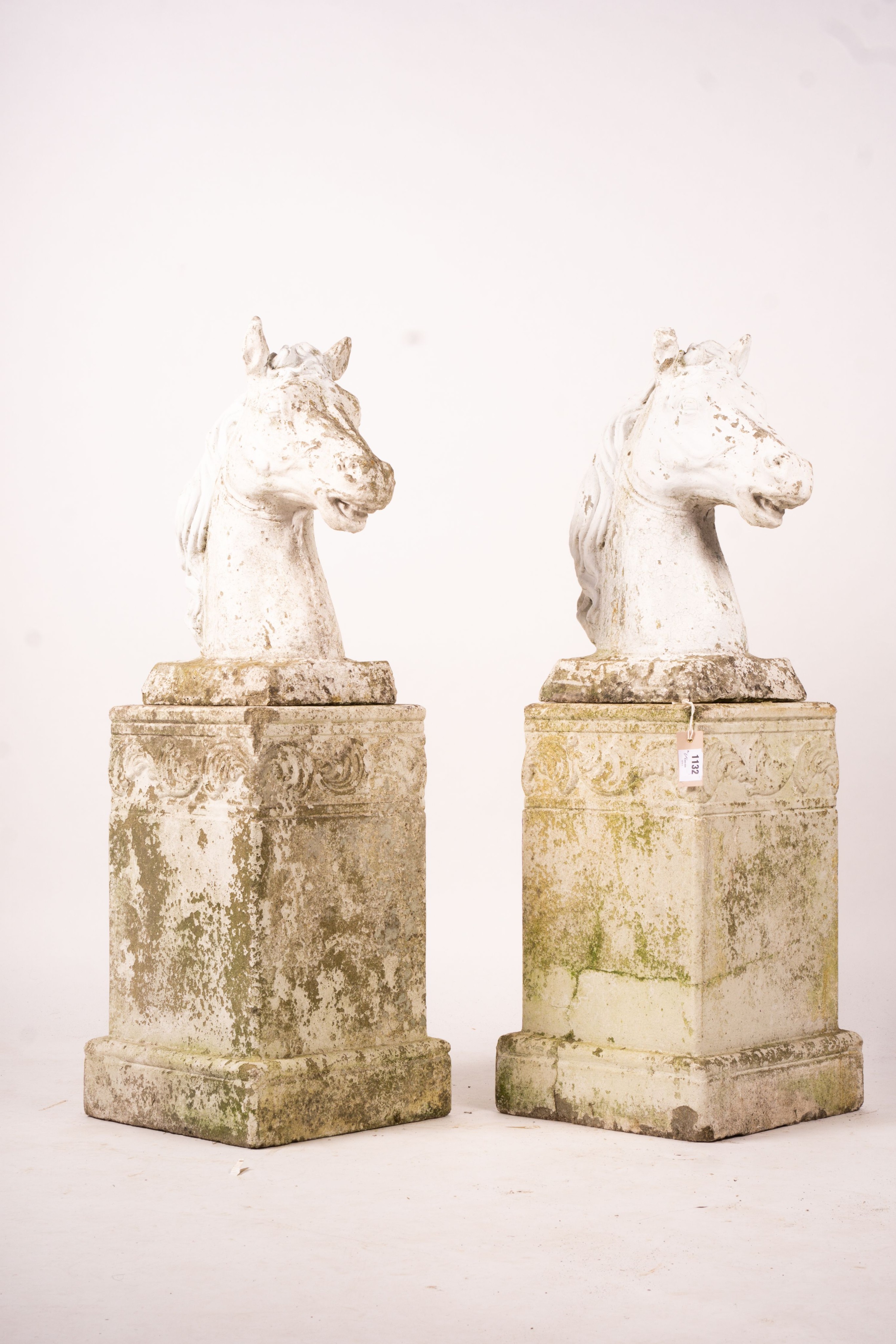 A pair of reconstituted stone horse's heads on plinth bases in the style of Austin and Seeley, height 104cm